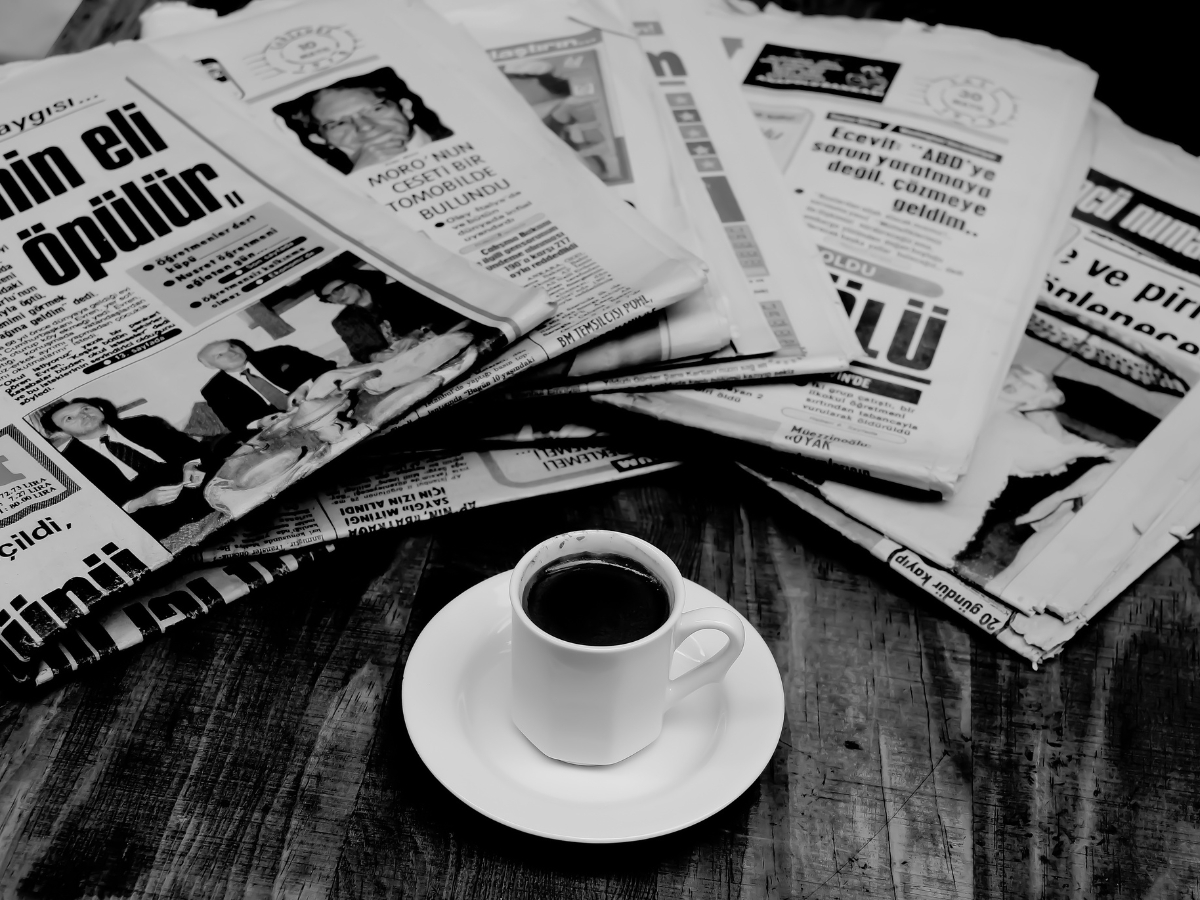 newspapers spread on a table with a cup of coffee